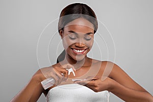 Beautiful Black Female Applying Hydrophilic Oil On Cotton Pad For Face Cleansing