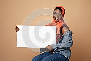 Beautiful black muslim woman got vaccinated, holding blank placard