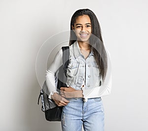 Beautiful black school girl posing on studio white background with backpack