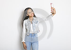 Beautiful black teen posing on studio white background with cellphone doing selfie