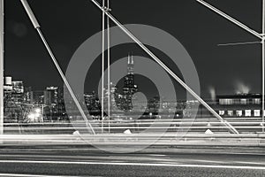 Beautiful black and white night photograph looking through a cable supported bridge towards the Chicago skyline and skyscraper