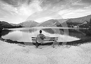 Beautiful black and white at park. Man is sitting on bench and bicycle lane, mountain lake in the Alps, Zell am See,