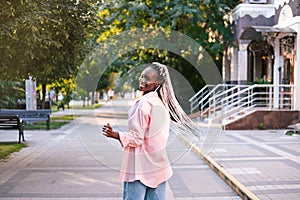 Beautiful black woman with braided hair posing at street.
