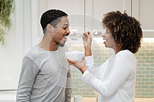 Beautiful black woman feeding her handsome husband, have breakfast together
