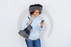 Beautiful black woman with purse looking at cellphone and laughing