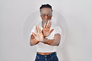 Beautiful black woman standing over isolated background rejection expression crossing arms and palms doing negative sign, angry