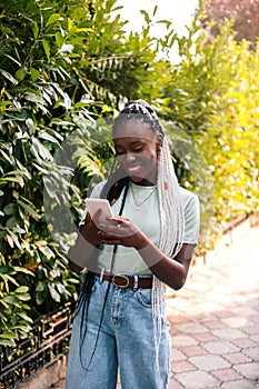 Beautiful black woman using smartphone at street.