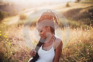 Beautiful black young woman in the park portrait long braids smiling flower