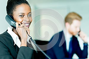A beautiful, black, young woman working at a call center in an o
