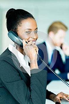 A beautiful, black, young woman working at a call center in an o