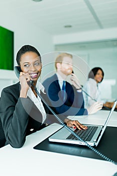 A beautiful, black, young woman working at a call center in an o