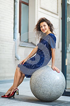 Beautiful blackhaired model girl posing for cloth and bags promotion at city streets background