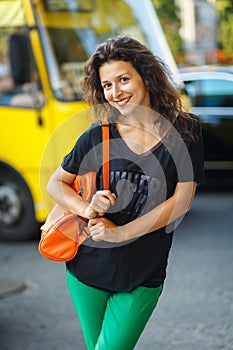 Beautiful blackhaired model girl posing for cloth and bags promotion at city streets background