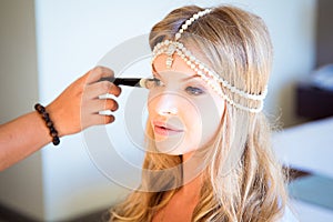 Beautiful blond bride doing makeup in her wedding day near mirror. Bride makeup.