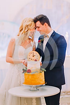 Beautiful blond bride and groom cut the wedding cake together