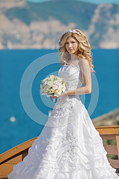 Beautiful blond bride in wedding dress with bouquet of flowers o