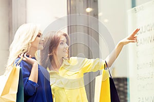 Pretty women with a shopping bags. Friends walking outdoor in a city. Discount, sale, shopping and money spending concept.