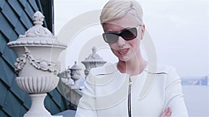 Beautiful blond business women wearing sunglasses white jacket waiting meeting speak phone city streets