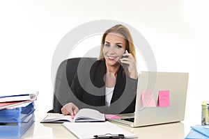 Beautiful blond businesswoman talking on mobile phone smiling holding pen writing notes on notepad