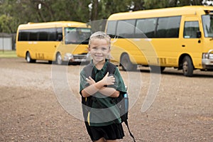 Beautiful blond Caucasian female child waiting for school bus carrying backpack smiling happy in student young girl and schoolgirl