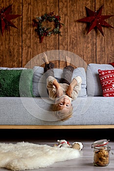 Beautiful blond child, young school boy, playing in a decorated home with knitted toys