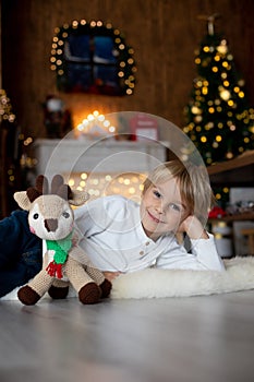 Beautiful blond child, young school boy, playing in a decorated home with knitted toys