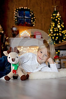 Beautiful blond child, young school boy, playing in a decorated home with knitted toys