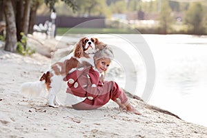 Beautiful blond girl child hugs and plays with a dog on the beach in summer, enjoying outdoor fun and affectionate