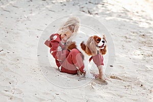 Beautiful blond girl child hugs and plays with a dog on the beach in summer, enjoying outdoor fun and affectionate