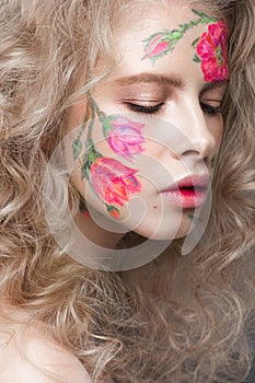 Beautiful blond girl with curls and a floral pattern on the face. Beauty flowers.