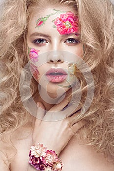 Beautiful blond girl with curls and a floral pattern on the face. Beauty flowers.