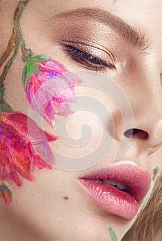 Beautiful blond girl with curls and a floral pattern on the face. Beauty flowers.