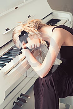 Krásný v páska do vlasů ležící na klávesnice z bílý klavír její oči zavřeno. na 1920