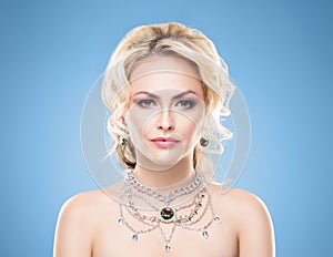 Beautiful blond girl with luxury golden necklace over blue background.