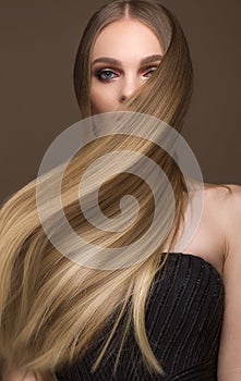 Beautiful blond girl with a perfectly smooth hair, classic make-up. Beauty face