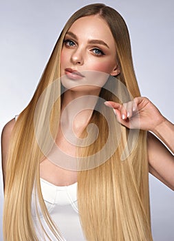 Beautiful blond girl with a perfectly smooth hair, and classic make-up. Beauty face and hair.