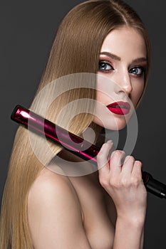 Beautiful blond girl with a perfectly smooth hair, curling, classic make-up and red lips. Beauty face