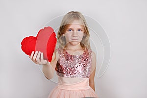 beautiful blond girl with red heart on a white background. Child with a heart for Valentine`s day