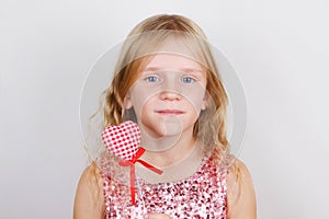 Beautiful blond girl with red heart on a white background. Child with a heart for Valentine`s day