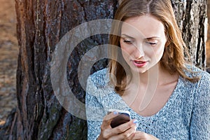 Beautiful blond girl resting in forest speak by cell phone and, sitting with cup of tea and book. Confident caucasian