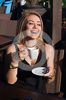 Beautiful blond girl sitting in a street cafe and laughing