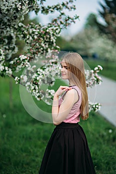 Beautiful blond hair girl standing in front of the blooming tree. beautiful spring