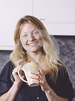 Beautiful blond having coffee in her kitchen