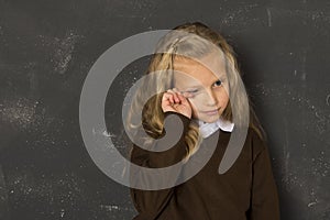 Beautiful blond schoolgirl crying sad moody and tired in front of school class blackboard