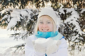 Beautiful blond smiling girl holding snow on the palms