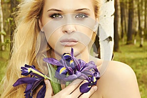 Beautiful blond woman with blue flowers in a forest