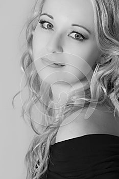 Beautiful blond woman in curly hair and black top on grey background artistic conversion