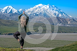 Beautiful blond woman does a yoga pose in front of Denali Mountain in Alaska