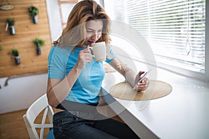 Beautiful blond woman drinking coffee and reading news
