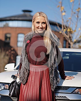 Beautiful blond woman at her white car, jeep, sport utility